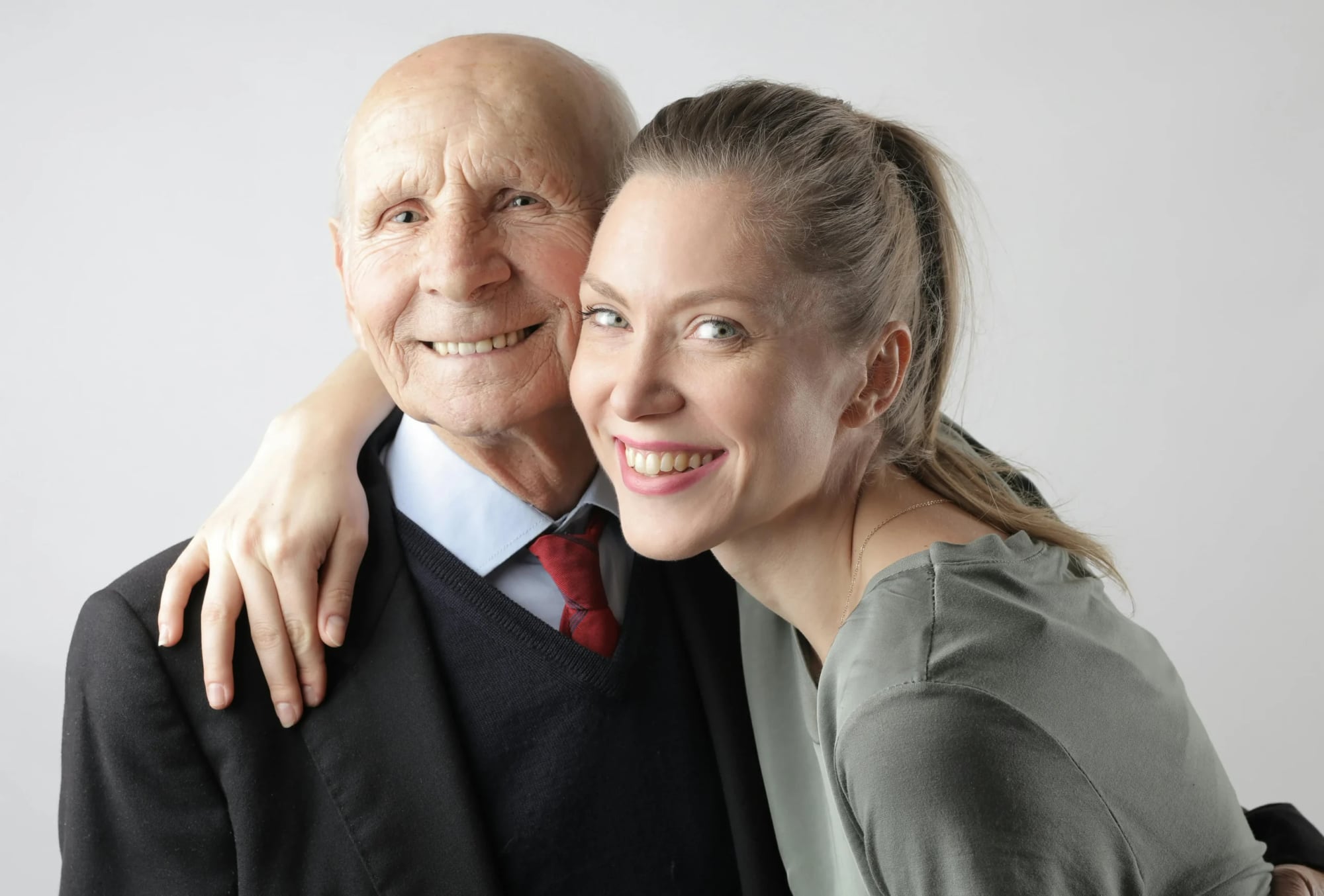 An adult daughter with her arm around her smiling father