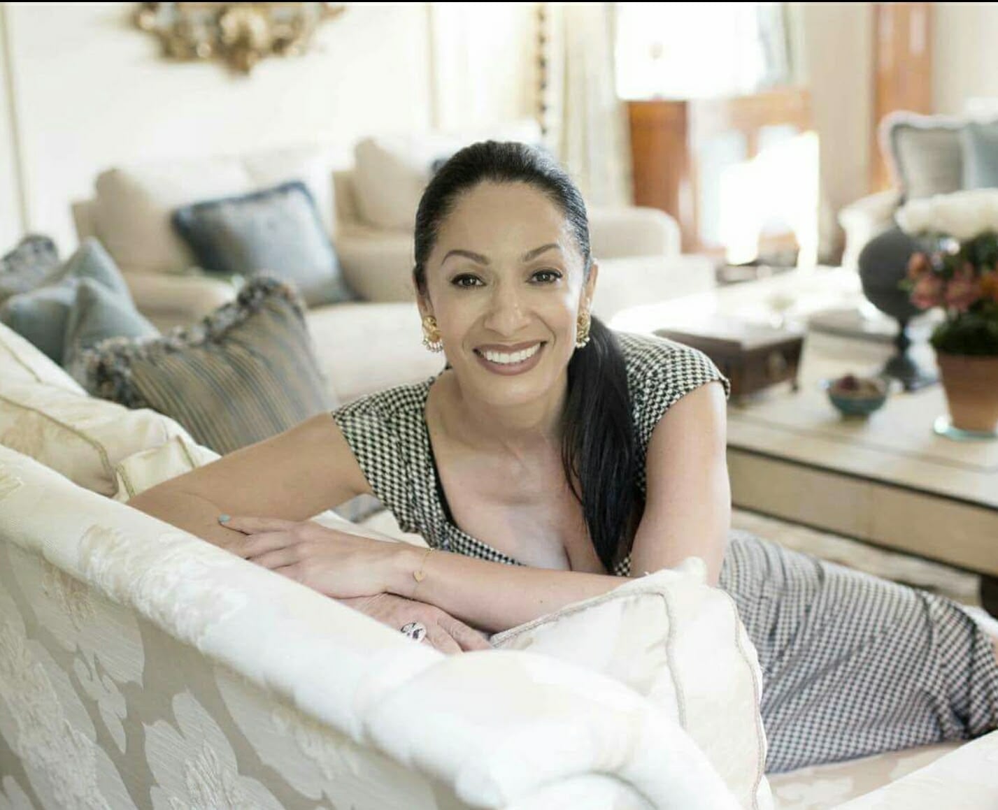 Hamssa Benrekia smiling, leaning on a sofa in a bright living room